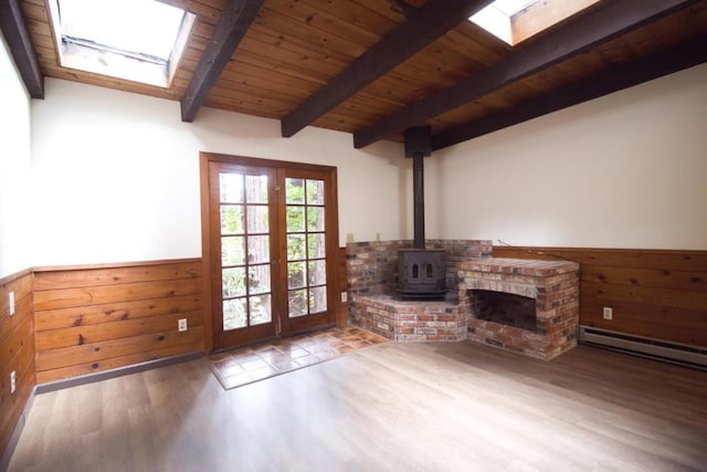 unfurnished living room with a skylight, hardwood / wood-style floors, wooden walls, wooden ceiling, and beamed ceiling