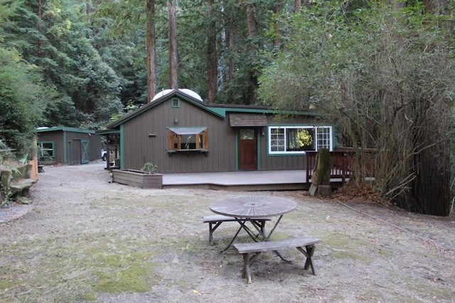 rear view of property featuring a deck and an outbuilding