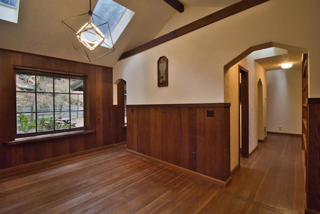 foyer with dark wood-type flooring, lofted ceiling with skylight, and wooden walls