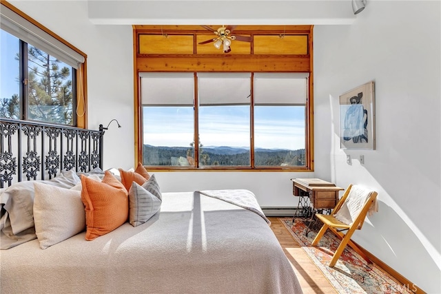 bedroom featuring baseboard heating, a mountain view, hardwood / wood-style flooring, and beamed ceiling