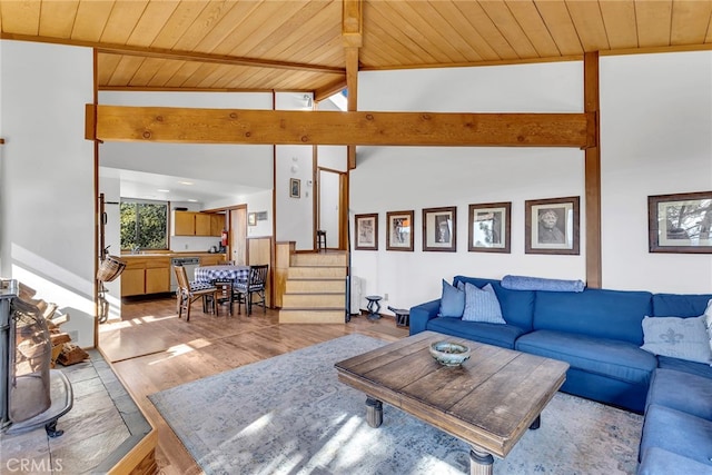 living room with wood ceiling, beamed ceiling, light hardwood / wood-style floors, a wood stove, and high vaulted ceiling