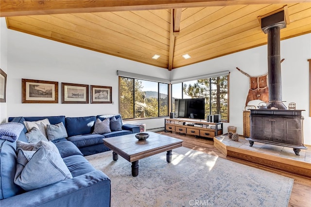 living room featuring high vaulted ceiling, a wealth of natural light, a wood stove, and wooden ceiling