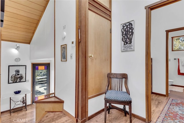 corridor with high vaulted ceiling, light hardwood / wood-style flooring, and wood ceiling