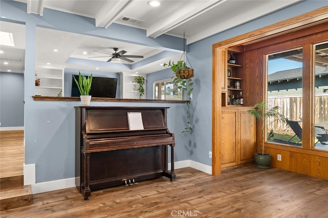 misc room with ceiling fan, built in shelves, beam ceiling, and hardwood / wood-style floors