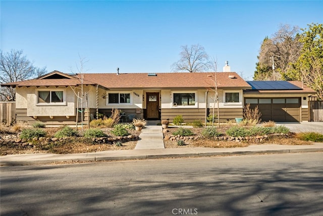 ranch-style house featuring a garage and solar panels