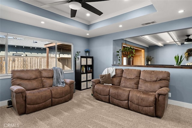 living room with ceiling fan, a raised ceiling, and light carpet