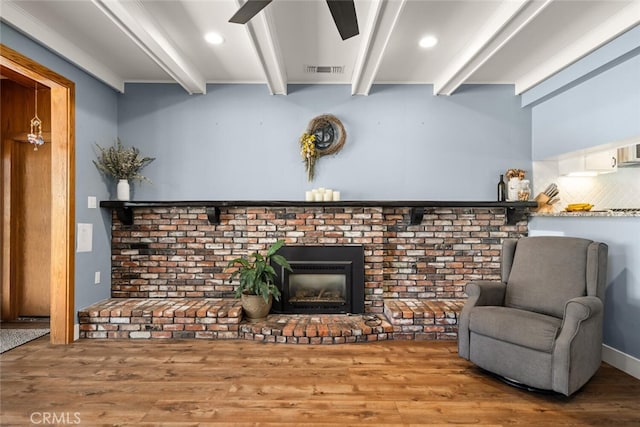 sitting room with a fireplace, hardwood / wood-style floors, and beam ceiling