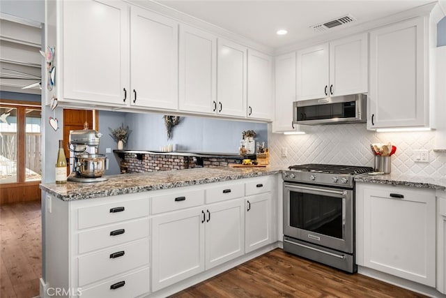 kitchen with stainless steel appliances, white cabinetry, light stone counters, and dark hardwood / wood-style floors