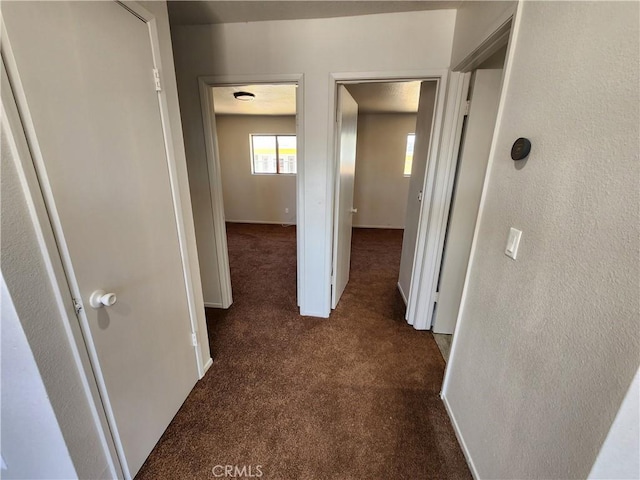 hall featuring dark colored carpet