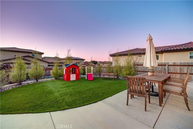 patio terrace at dusk featuring a yard