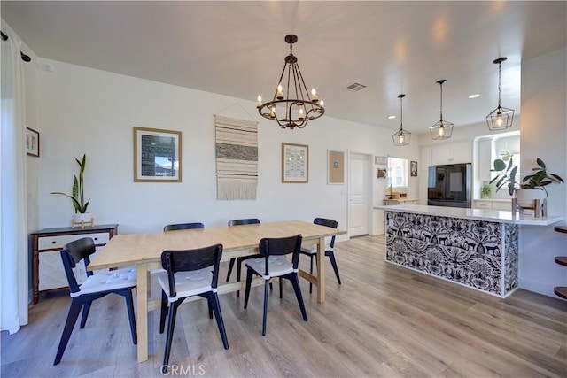 dining room with a notable chandelier and light wood-type flooring