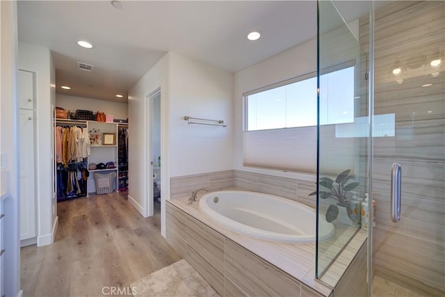 bathroom featuring wood-type flooring and shower with separate bathtub