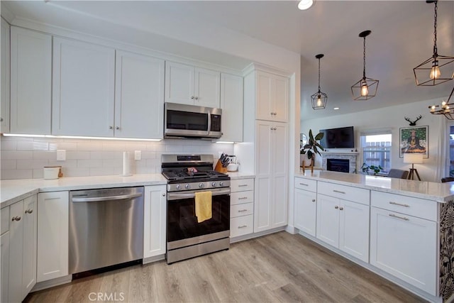 kitchen featuring pendant lighting, white cabinetry, appliances with stainless steel finishes, and light hardwood / wood-style flooring