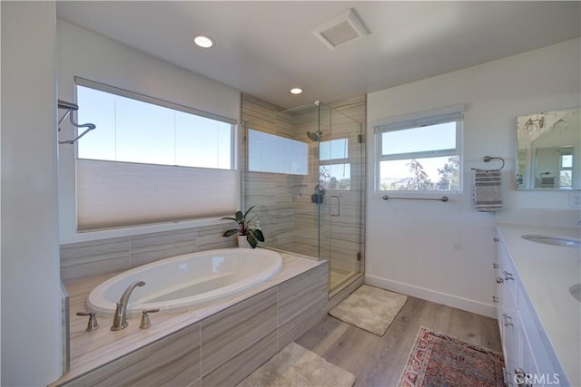 bathroom with vanity, hardwood / wood-style flooring, and plus walk in shower