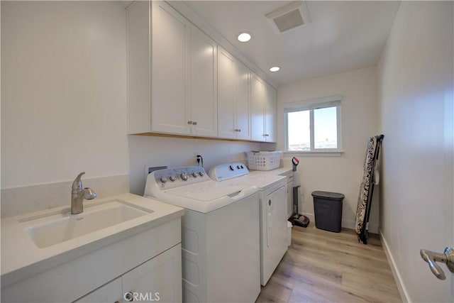 washroom featuring light hardwood / wood-style floors, cabinets, washer and clothes dryer, and sink