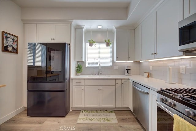 kitchen featuring white cabinetry, sink, light hardwood / wood-style flooring, and stainless steel appliances