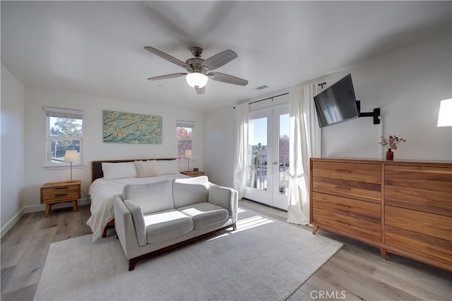 bedroom with multiple windows, access to outside, light hardwood / wood-style floors, and french doors