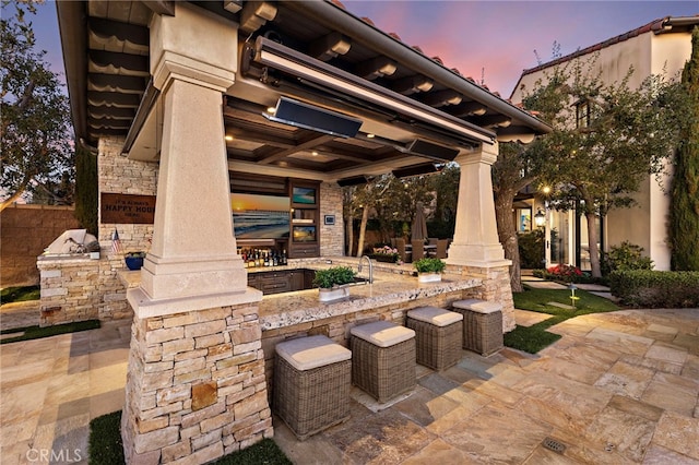 patio terrace at dusk featuring outdoor dry bar and area for grilling