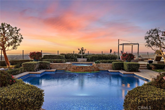 pool at dusk with an outdoor pool and an in ground hot tub