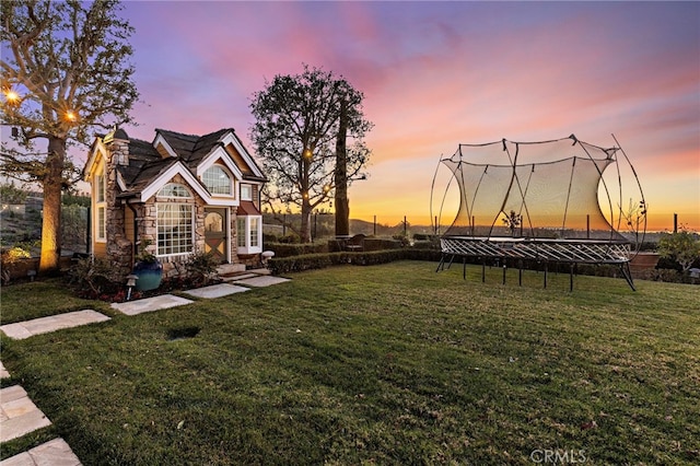 yard at dusk featuring a trampoline