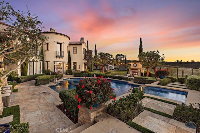 view of swimming pool with a patio area, fence, and a lit fireplace