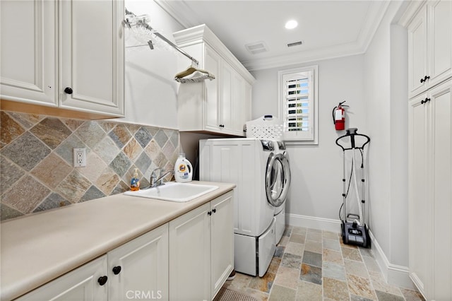 washroom with cabinet space, independent washer and dryer, stone tile flooring, crown molding, and a sink