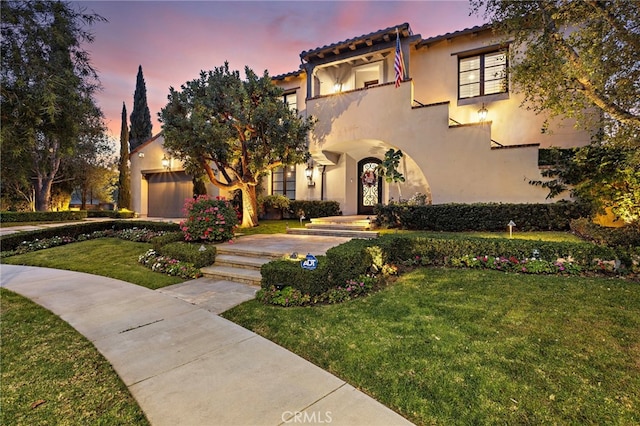 mediterranean / spanish-style house with a balcony, a garage, a lawn, and stucco siding