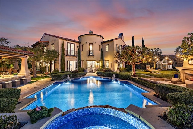 pool at dusk with an in ground hot tub