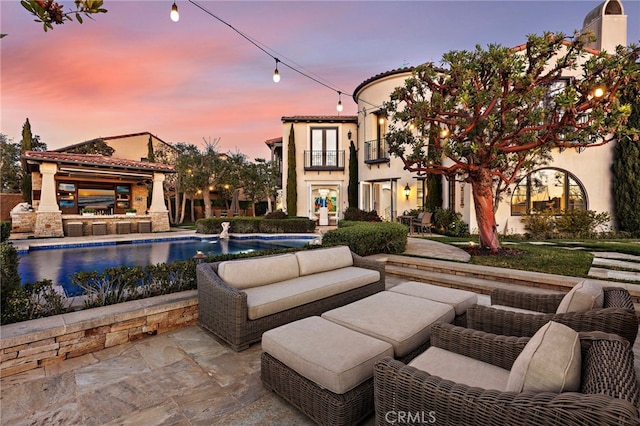 exterior space with an outdoor pool, a balcony, and an outdoor hangout area