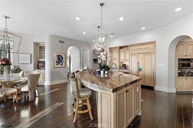 kitchen with stainless steel oven, arched walkways, and cream cabinetry