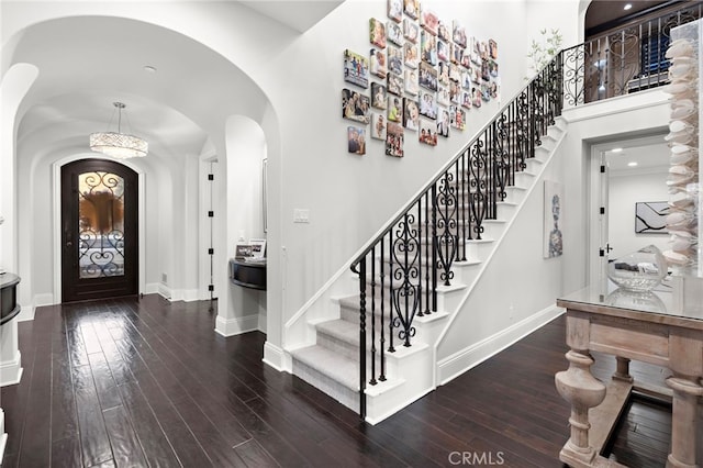 foyer entrance with hardwood / wood-style flooring, stairway, baseboards, and arched walkways