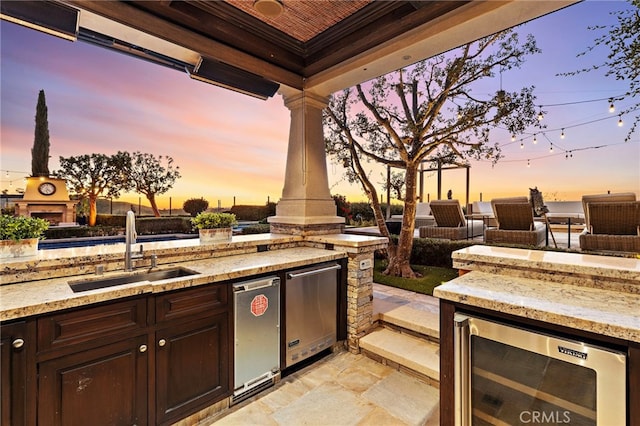 view of patio featuring beverage cooler, exterior kitchen, and a sink