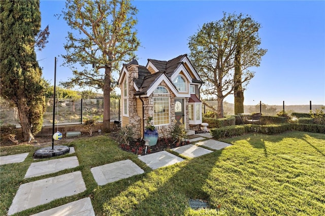 view of front of home featuring stone siding, a chimney, fence, and a front yard