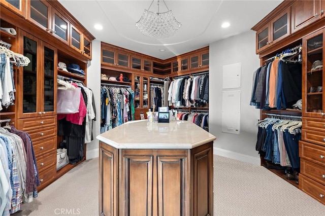 walk in closet with light carpet and an inviting chandelier