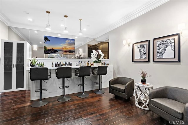 bar with dark wood-style flooring, decorative light fixtures, recessed lighting, ornamental molding, and wet bar