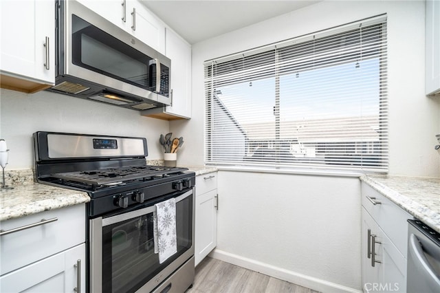 kitchen with white cabinetry, light hardwood / wood-style flooring, light stone countertops, and appliances with stainless steel finishes