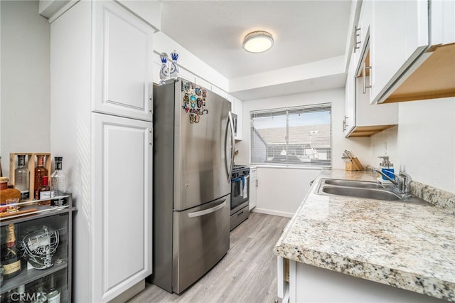 kitchen featuring sink, light hardwood / wood-style flooring, white cabinets, and appliances with stainless steel finishes