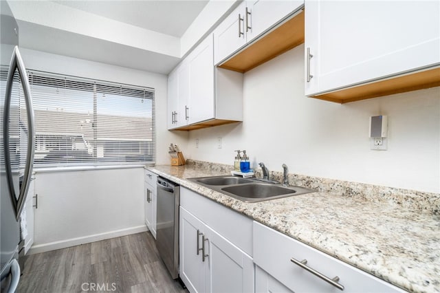 kitchen featuring sink, white cabinets, hardwood / wood-style flooring, light stone countertops, and stainless steel appliances