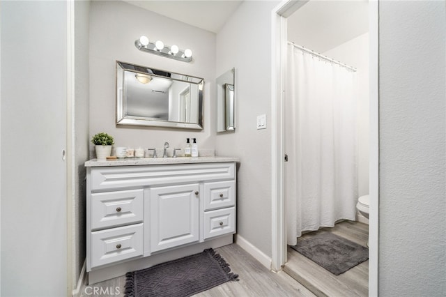 bathroom with hardwood / wood-style flooring, toilet, and vanity