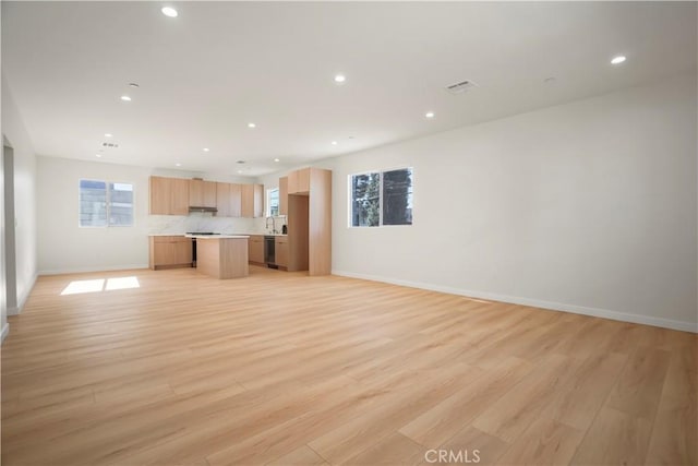 unfurnished living room featuring sink and light hardwood / wood-style flooring