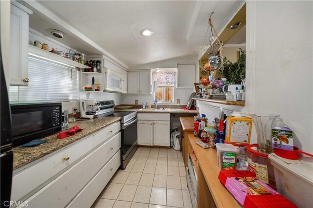 kitchen with light tile patterned floors, electric range, white cabinets, and vaulted ceiling