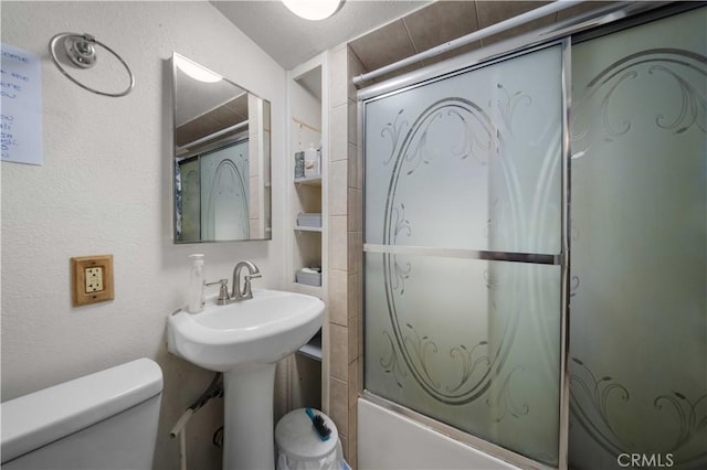 full bathroom with sink, bath / shower combo with glass door, and toilet