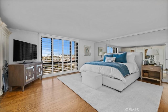 bedroom featuring access to exterior, floor to ceiling windows, crown molding, and wood finished floors