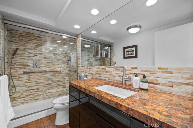 bathroom featuring decorative backsplash, vanity, toilet, and a shower stall