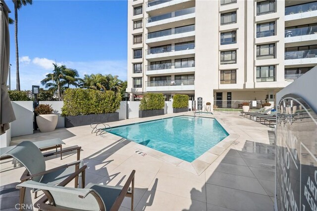 community pool with fence and a patio area