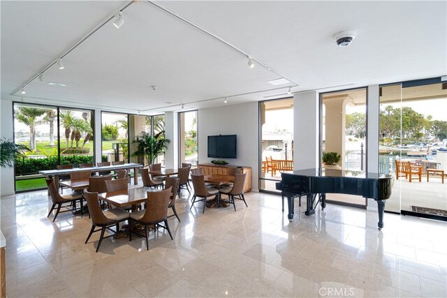 dining space with floor to ceiling windows and rail lighting