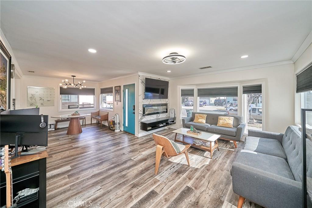 living room featuring an inviting chandelier, crown molding, a fireplace, and hardwood / wood-style flooring