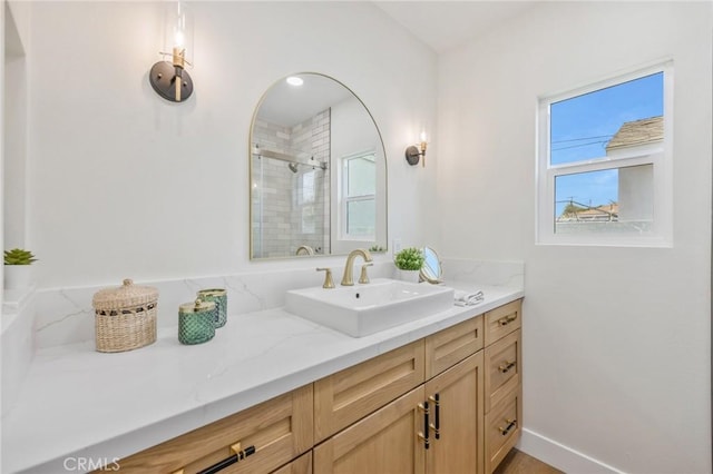 bathroom featuring a shower with door and vanity