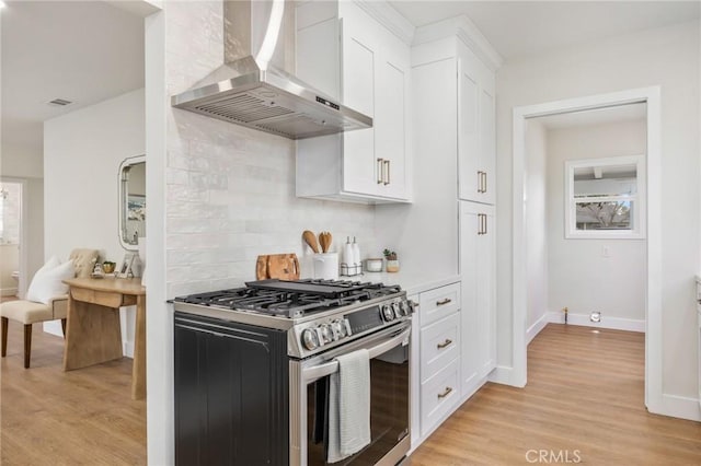 kitchen featuring gas range, light hardwood / wood-style floors, wall chimney range hood, and white cabinetry