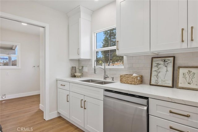 kitchen featuring dishwasher, sink, backsplash, white cabinets, and light stone counters